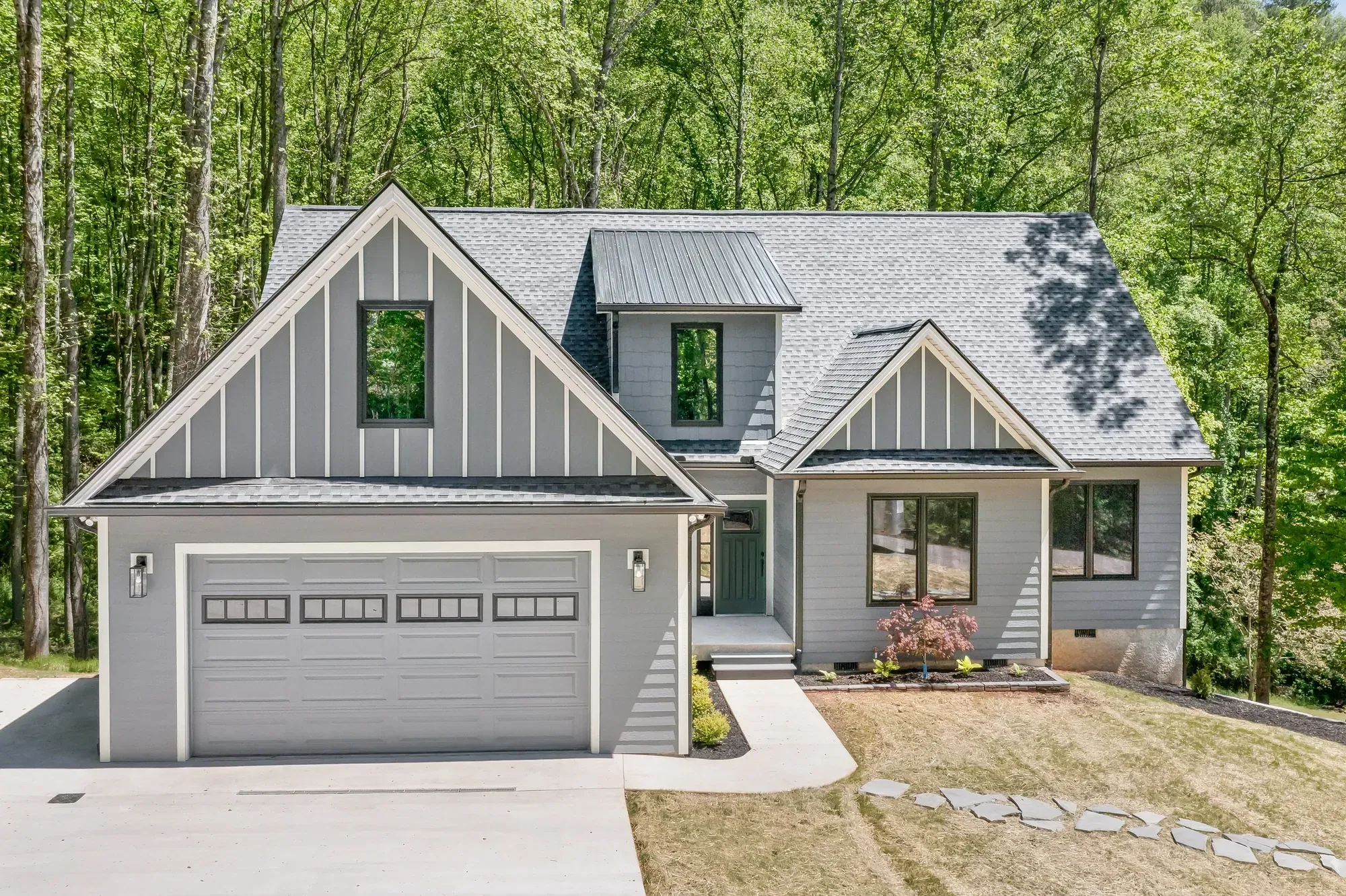 New custom home with gray siding and board-and-batten gables on a wooded lot in Candler, NC, built by Buckingham Builders