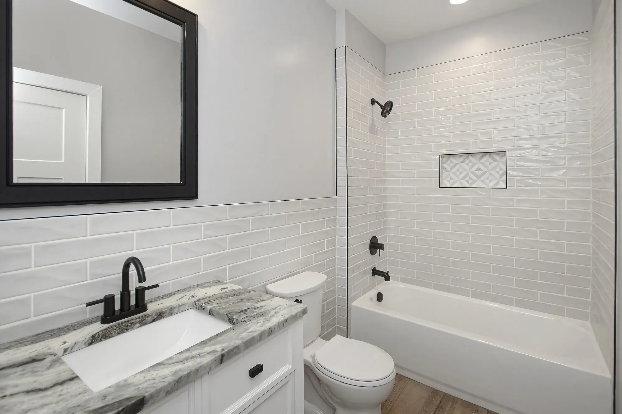 Hall bath with a subway-tile tub surround and a marble-look vanity top in a new Candler, NC home