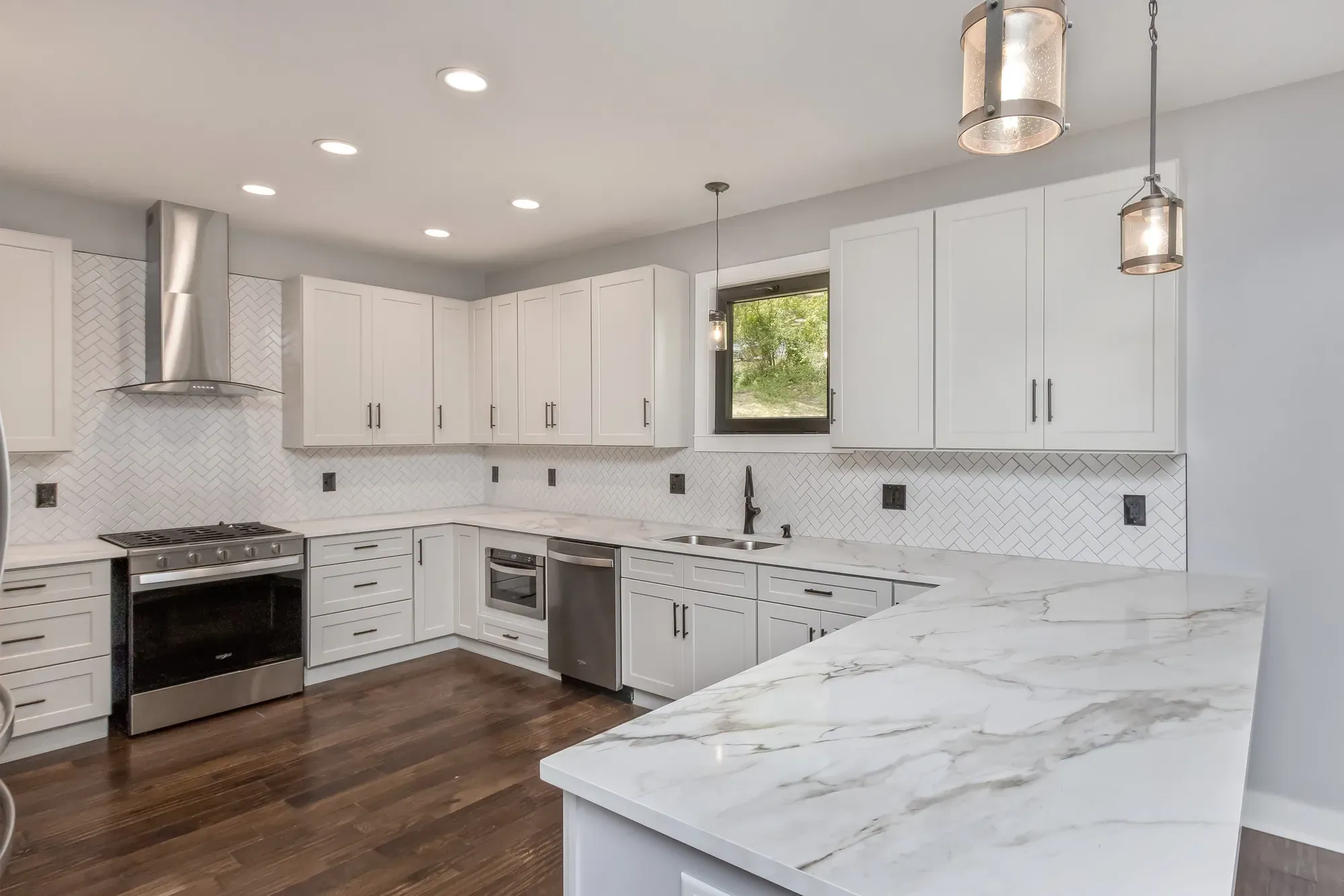 Kitchen with a chimney range hood, white cabinets and a gas range in a new Candler, NC home