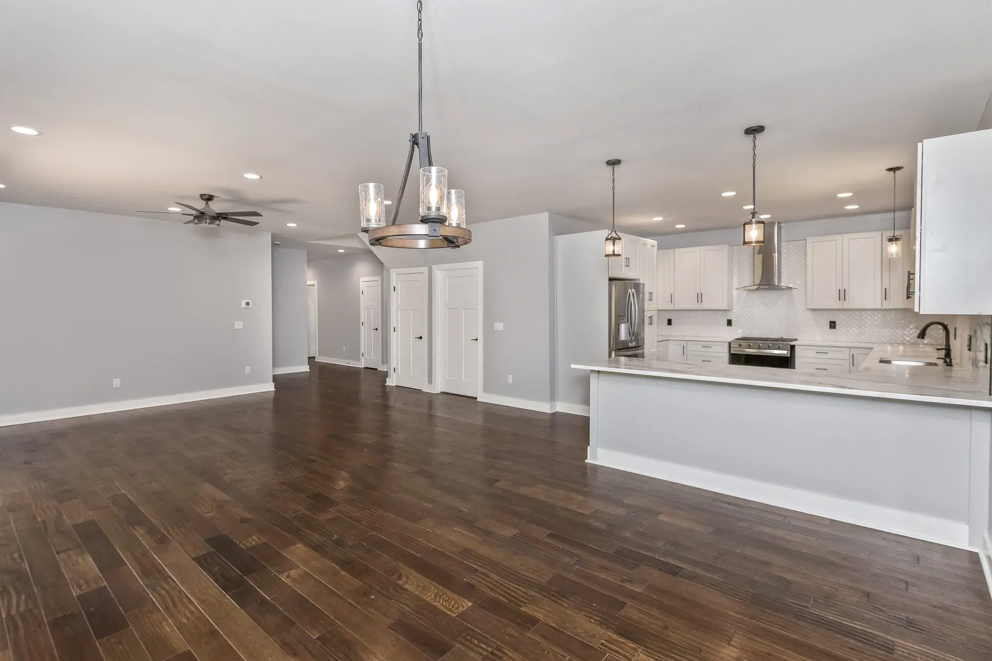 Open kitchen and dining area with pendant lights and hardwood floors in a new Candler, NC home