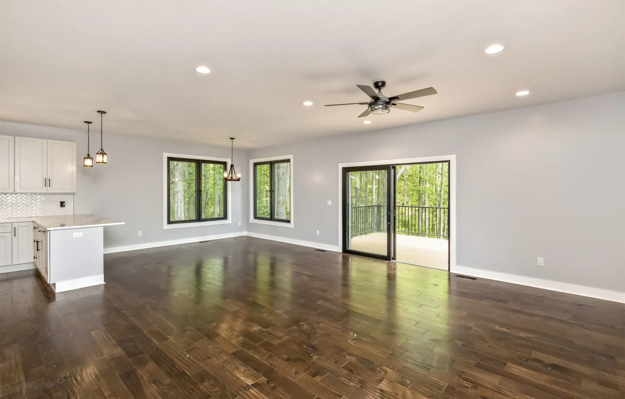 Open living room with hardwood floors and black-framed windows in a new Candler, NC custom home
