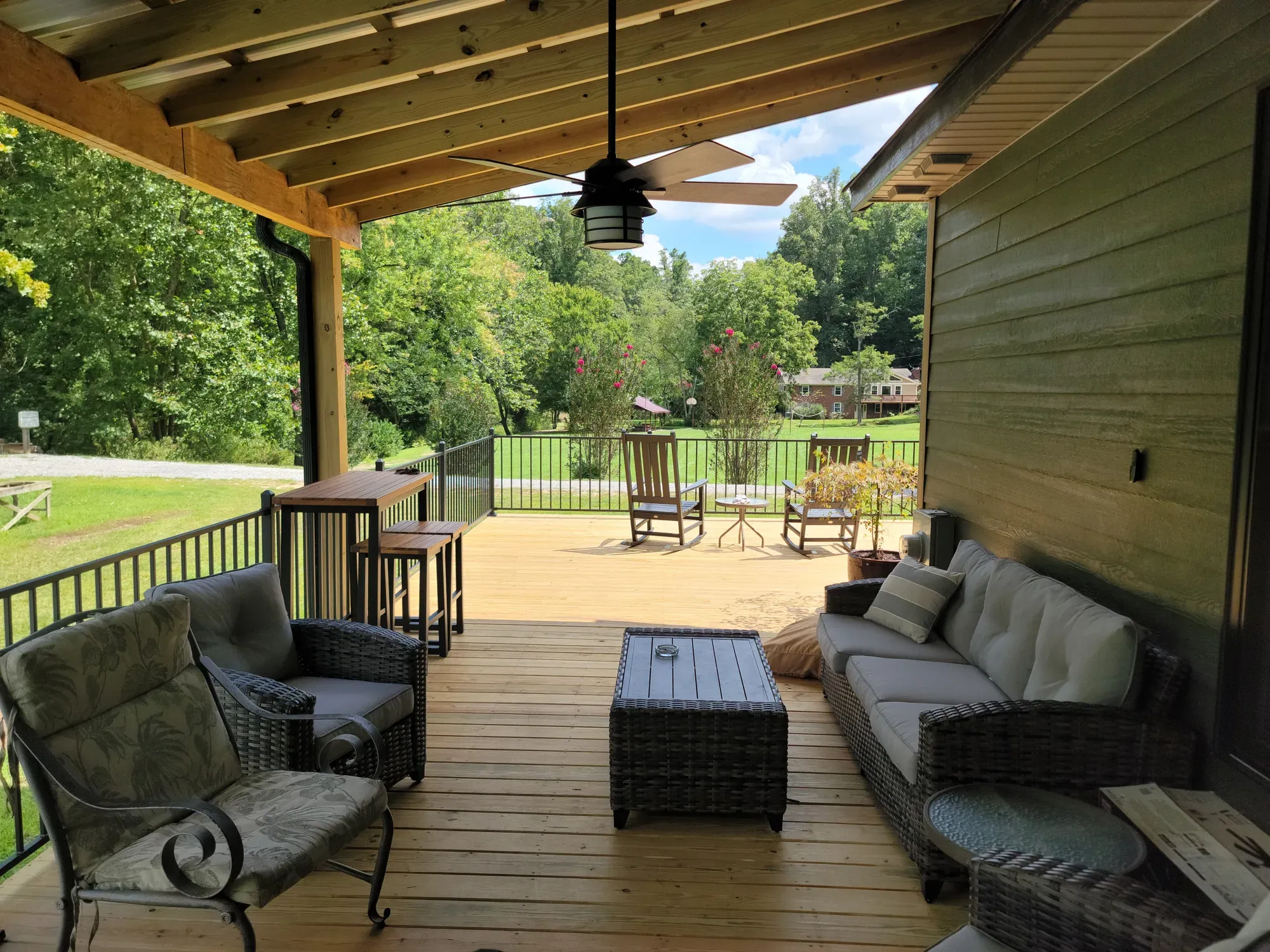 Covered porch with outdoor seating and a ceiling fan opening onto an open deck, built by Buckingham Builders