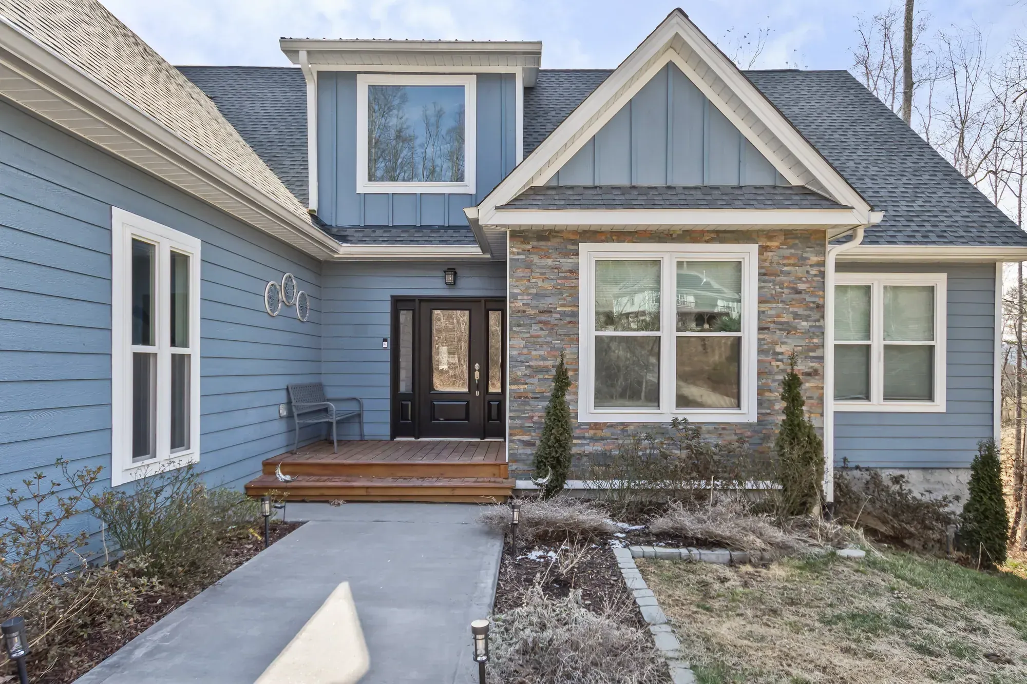 Front entry, stacked-stone bay and board-and-batten gable of a craftsman-style custom home in Weaverville, NC, built by Buckingham Builders