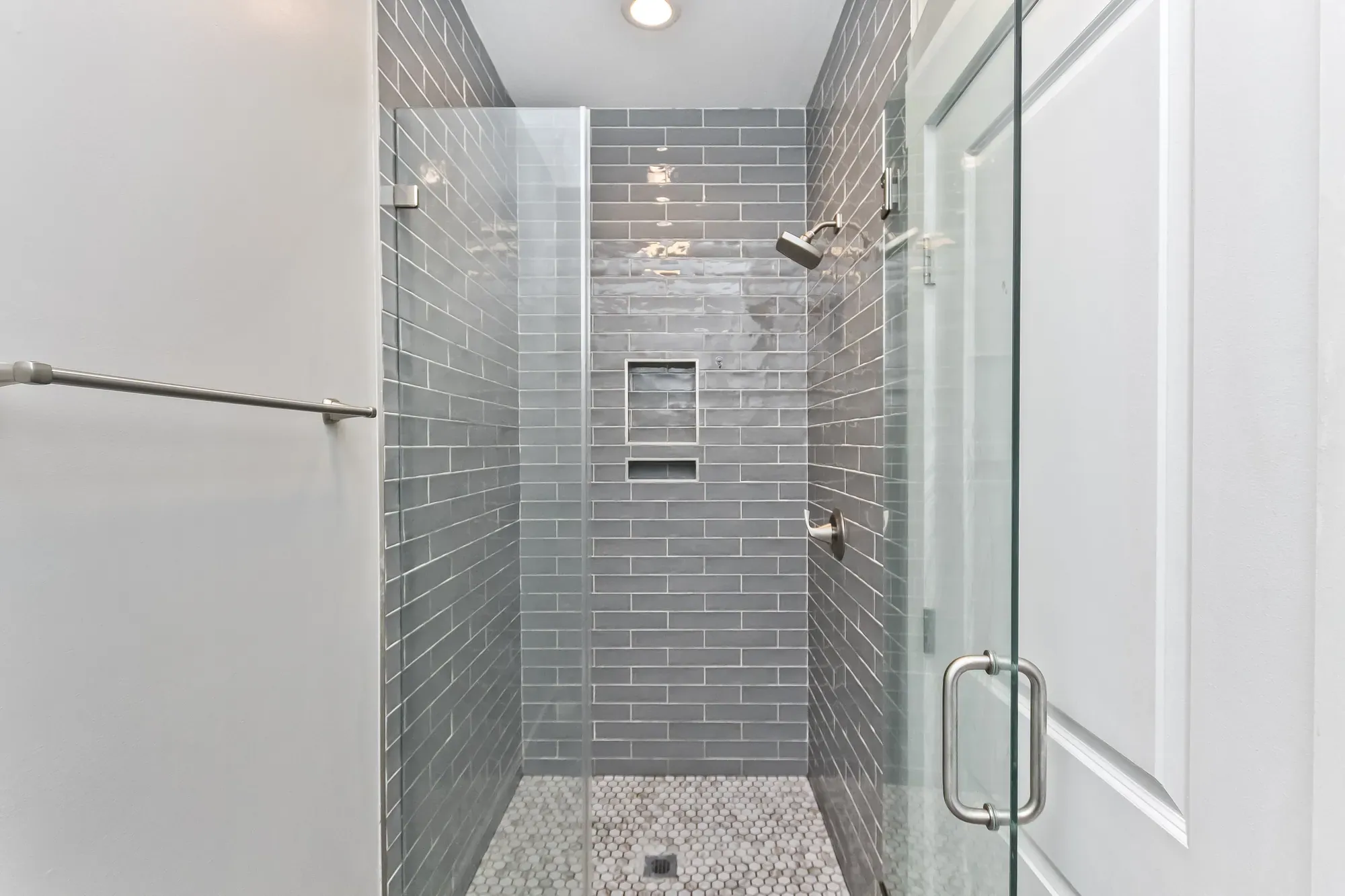 Walk-in shower with gray subway tile, a niche and a glass door in a Weaverville, NC custom home