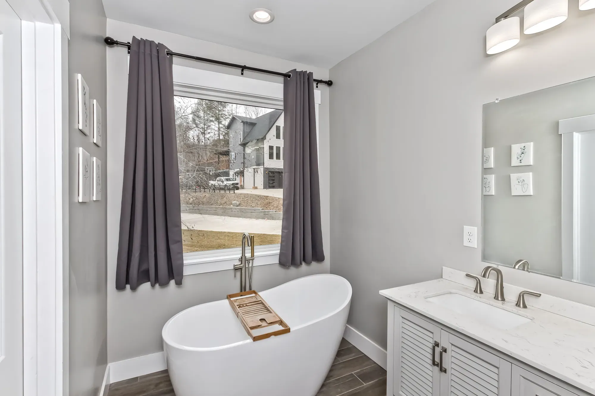 Primary bath with a freestanding tub under a window and a white double vanity in a Weaverville, NC home