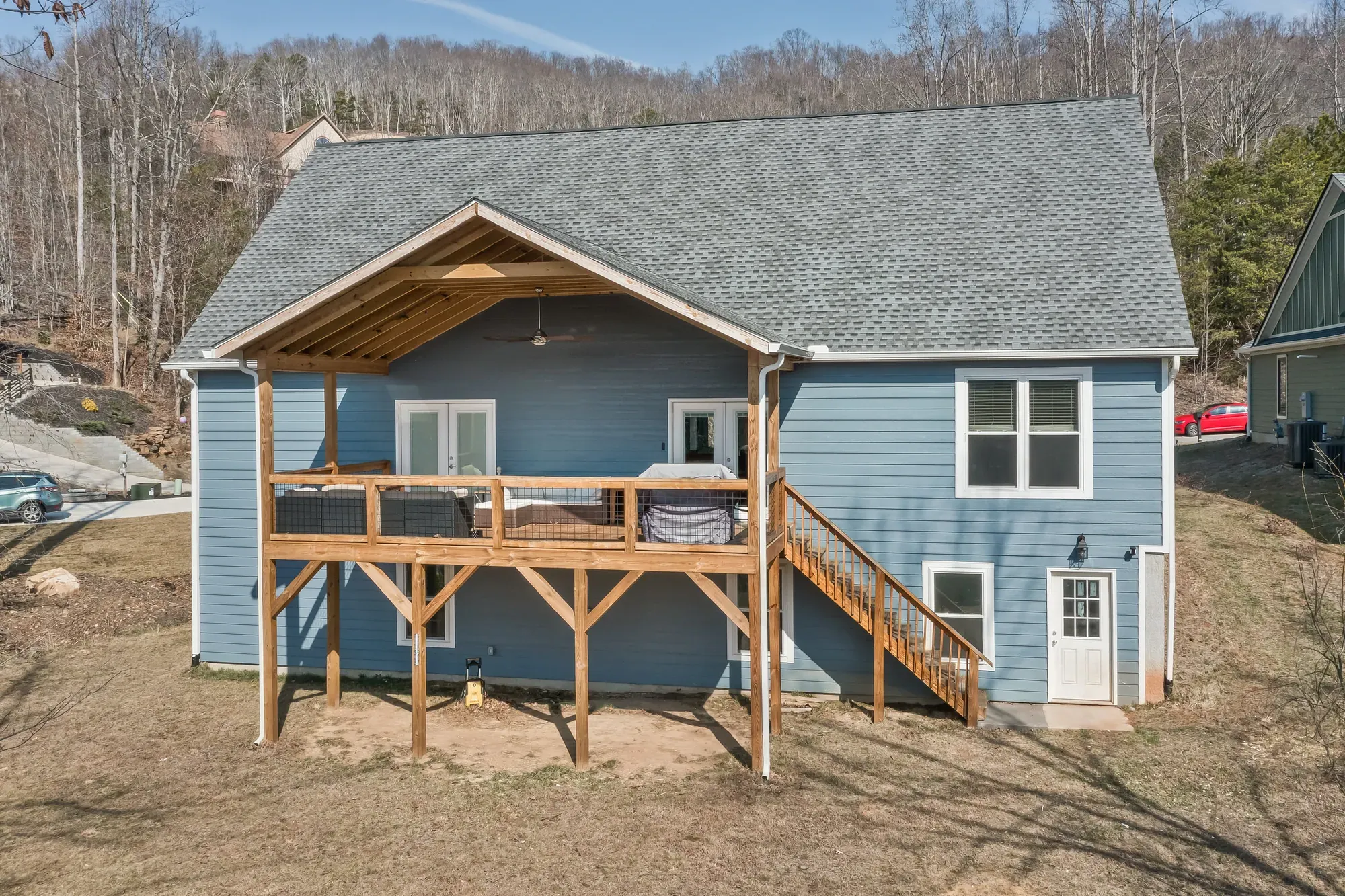 Rear of a Weaverville, NC custom home with a covered deck on timber posts above a walk-out lower level, built by Buckingham Builders